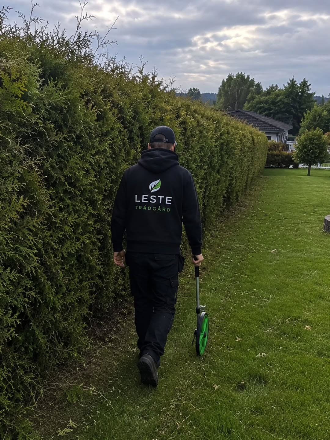 person med brandad tröja går längs en häck